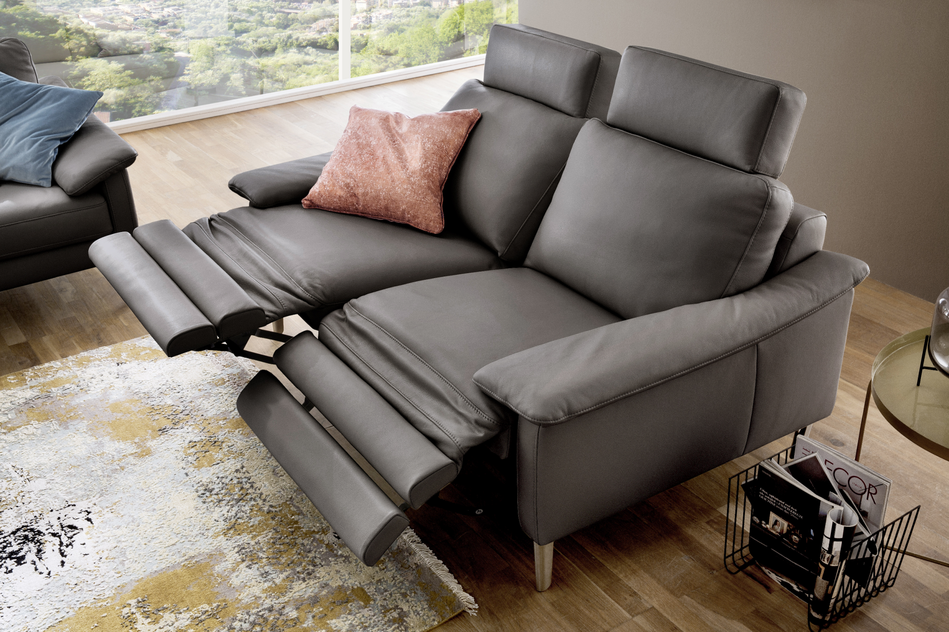 Ein graues Ledersofa mit integrierten Fußstützen und verstellbaren Kopfstützen, für Komfort von Möbel Lutz in Obernbreit.