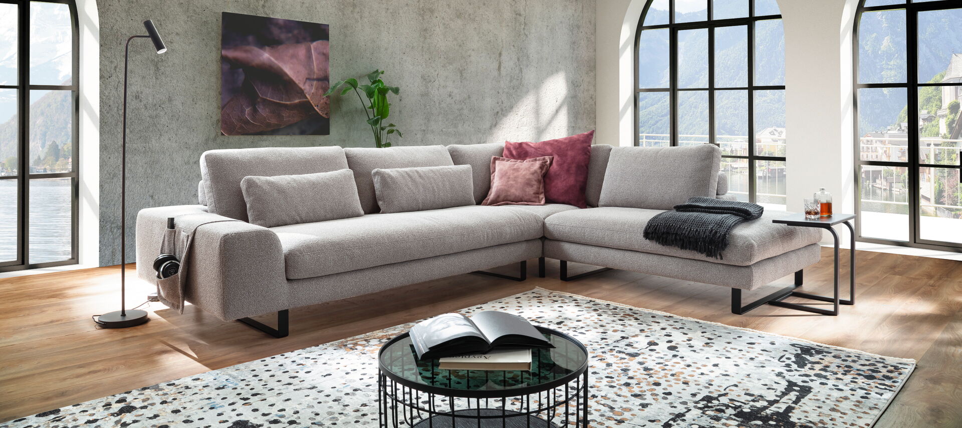 Eine stilvolle graue Wohnlandschaft in einem modernen Wohnzimmer mit großen Bogenfenstern, eingerichtet von Möbel Lutz aus Obernbreit.